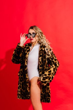 Young woman in a white bodysuit posing on studio background. Female fashion, beauty and body concept