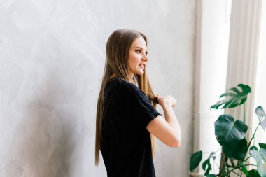 Uzun bacaklı ve uzun saçlı genç bir kadın. Sabahları rahat bir dairede kanepede poz veriyor.