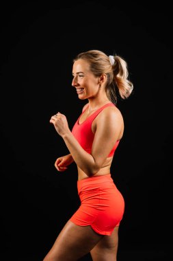 Full length portrait of smiling young woman in a sportswear isolated over studio background.