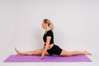 Sportif kız dambıllarla egzersiz yapıyor. Silüet stüdyosu koyu ve beyaz bir arka plan üzerinden çekiliyor.