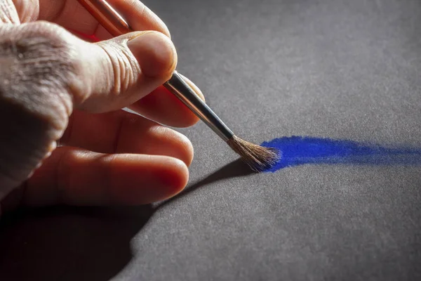 艺术和工艺主题 在灰色的地面上展示一只手绘有漆刷和蓝色油漆的绘画 — 图库照片