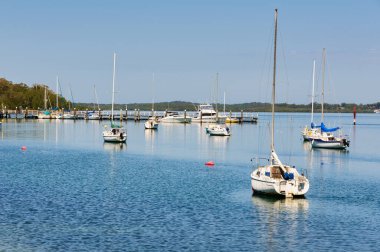 Huzurlu Karuah Nehri üzerindeki Sunset Sahili 'nde demirli yelkenliler - Askerler Noktası, NSW, Avustralya
