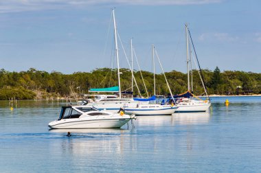 Huzurlu Karuah Nehri üzerindeki Sunset Sahili 'nde demirli tekneler - Askerler Noktası, NSW, Avustralya
