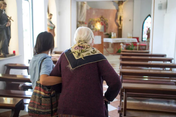 23 July 2018, San Martino di Schio, Italy: Health worker helps old woman to enter a church