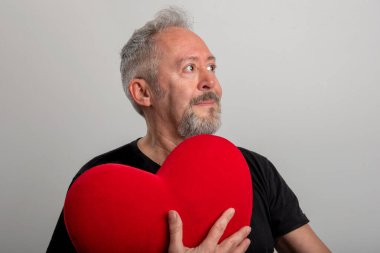 Yakışıklı, orta yaşlı, kır saçlı ve sakallı bir adam. Kırmızı bir kalbi var. Gri bir geçmişi var. Sevgililer Günü konsepti