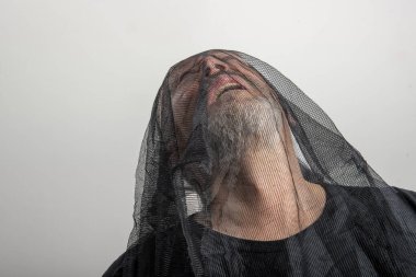 Kafasında siyah bir duvak olan gri sakallı bir adam.