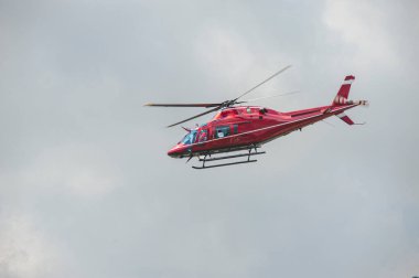 Kırmızı helikopter gökyüzünde uçuyor.
