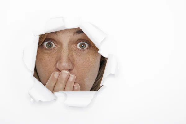 Mujer sorprendida a través del agujero en papel — Foto de Stock
