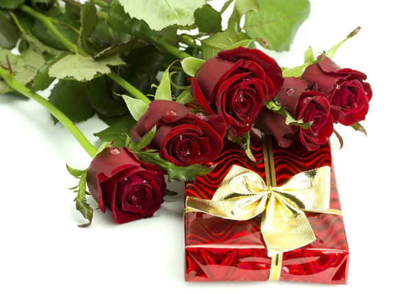 Bouquet of roses and red gift tied up by a bow — Stock Photo, Image