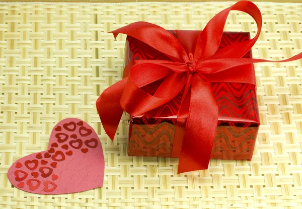 Gift and hearts on a wicker wood — Stock Photo, Image