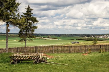 Rural landscape with countryside yard, fence and old wooden cart clipart