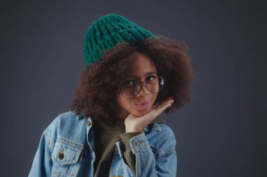 Siyah arka planda örgü şapka ve günlük kıyafetler giyen tatlı bir kız.