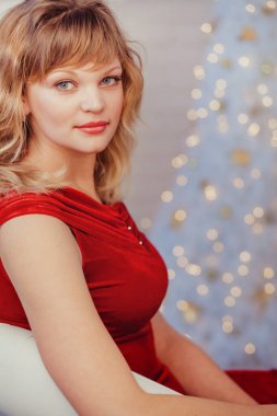  Güzel bir kadın Noel ağacında peri ışıklarına karşı sandalyede oturuyor.