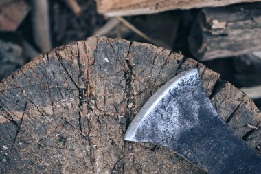 Ahşap saplı eski bir balta yakacak odun yığınının üzerinde duruyor.
