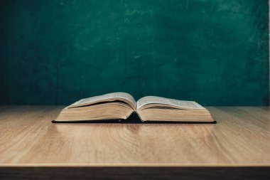 Tahta bir masada kutsal kitabı aç. Güzel yeşil duvar arkaplanı.