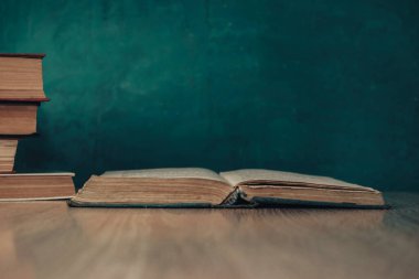 Beautiful vintage ancient books. Pattern background for design. The book on a wooden table and green wall background.