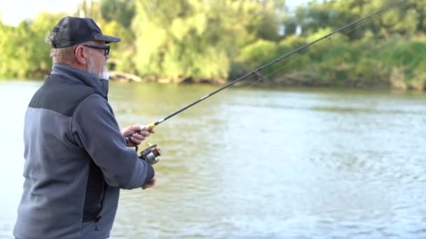 良い夏の日にリールロッド、回転やスプーン餌や釣りを保持眼鏡漁師と成熟した灰色の髭の男。男性趣味 — ストック動画