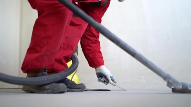 Limpeza chão de cimento com aspirador de pó. Um trabalhador remove poeira com um aspirador de pó. Um trabalhador com um aspirador industrial remove a poeira dos reparos. Preparação do piso para renovação — Vídeo de Stock