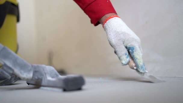 İşçiler iş eldivenleri ile beton zemindeki boyaları kazıyıcı ve elektrikli süpürge kullanarak çıkarıyorlar. Endüstriyel elektrik süpürgesi, yeni bir dairede yenileme. — Stok video
