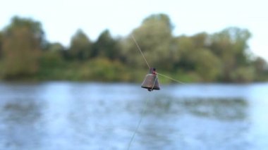 Oltaya takılmış eski bir pirinç çanın yakın çekimi. Zil çizgiden düşüyor. Balık ısırığı. Geleneksel balıkçılık malzemeleri. Aktivite hafta sonu, erkek hobisi