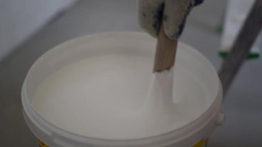 Beyaz boya karıştıran bir ressamın yakın çekimi. Yenileme ve bitirme konsepti