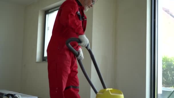 Trabalhador da construção limpa um canteiro de obras com um aspirador industrial — Vídeo de Stock