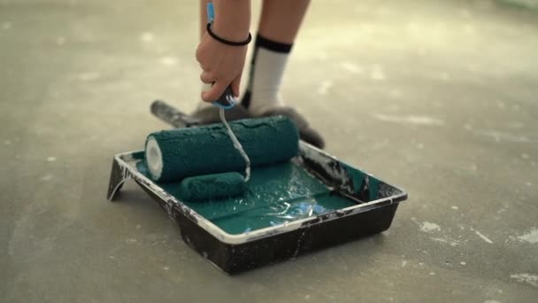Kvinnors hand fuktar en rulle i en bricka med blå färg. Kreativitet och renovering av hemmet. Verktyg för ytbehandling och dekoration — Stockvideo