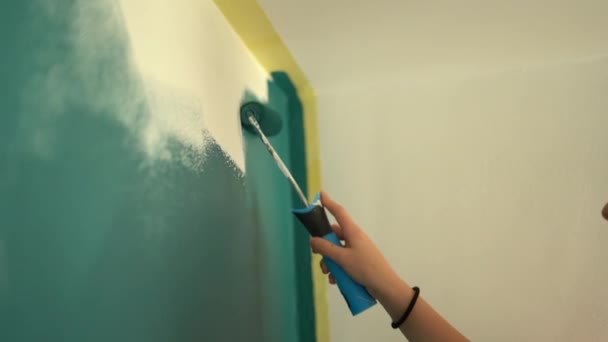 Gros plan la main de la jeune adolescente peint une couleur de sarcelle murale blanche. Concept de rénovation et de créativité. Outils de finition — Video