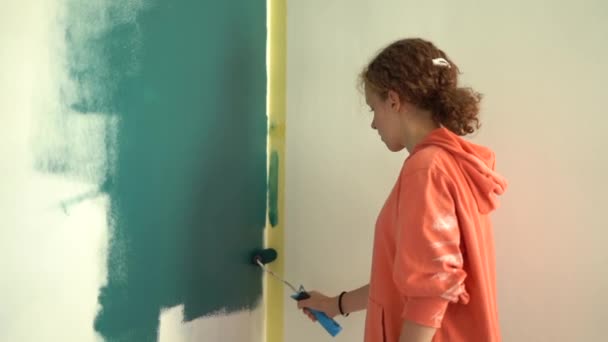 Teen Girl Ζωγραφική εσωτερική τοίχους σε επίπεδο χρησιμοποιώντας ρολό ζωγραφικής. Το ίδιο το παιδί φτιάχνει επισκευές στο δωμάτιό της, βάφει τον τοίχο με δαγκάνες. Ανακαίνιση σπιτιού ή ανακαίνιση έννοια — Αρχείο Βίντεο