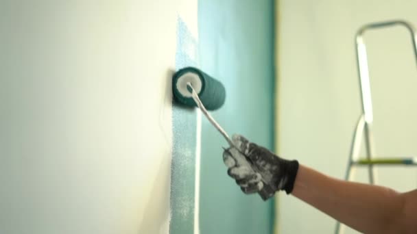 El hombre pinta una pared en su nuevo hogar. renovación y concepto de bienes raíces. Primer plano de un rodillo de pintura de pared — Vídeos de Stock