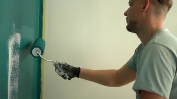 一个涂漆滚筒的男性房屋漆工的肖像。年轻人画墙蓝色、装修和房地产概念 — 图库视频影像