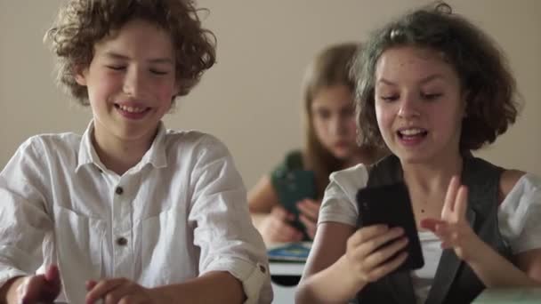 Chica tomando una selfie. Los adolescentes son fotografiados, un retrato de un niño y una niña en un escritorio con teléfonos inteligentes — Vídeo de stock