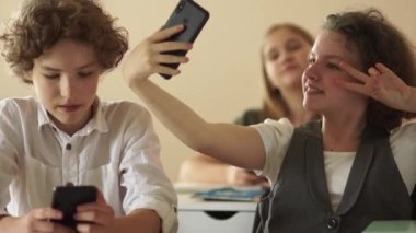 Ergen kız bir okul ofisinde gülümserken selfie çekiyor. Okula dönelim. Gençler ve akıllı telefonlar.