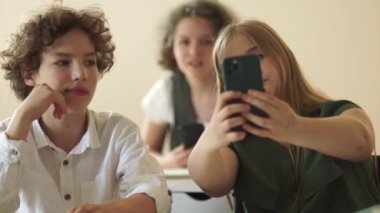 Ergen kız bir okul ofisinde gülümserken selfie çekiyor. Okula dönelim. Gençler ve akıllı telefonlar.
