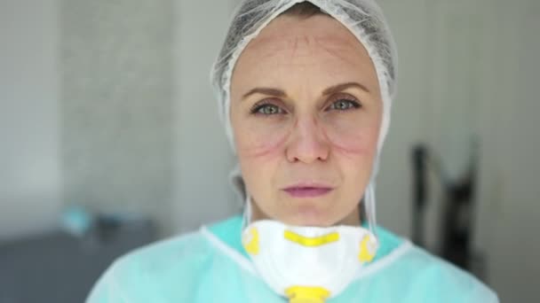 Female doctor during a coronavirus pandemic covid-19. Portrait of a tired nurse with beautiful eyes and deep mask marks on her face. The hard work of a doctor during a pandemic — Stockvideo