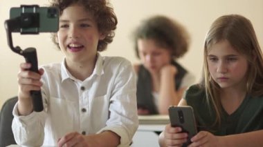 Şirin okul çocukları video blogcuları, kız ve erkek çocuklar, tatilde sınıflarında blogları için videolar kaydediyorlar.