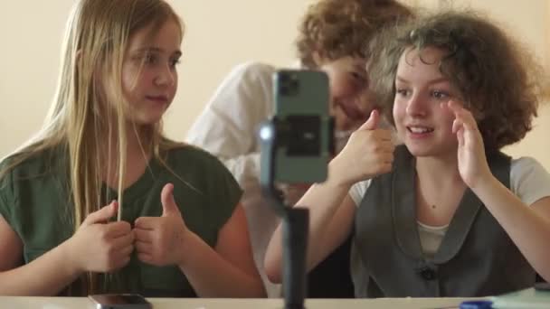 Une écolière aux cheveux bouclés apprend à son camarade de classe à filmer les tendances des réseaux sociaux. Concept de blogueurs enfants — Video