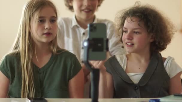 Des écolières mignonnes enregistrent des vidéos sur une caméra smartphone. Les adolescents capturent les tendances des médias sociaux, influencent les adolescents à l'école en classe — Video
