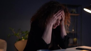 Gecenin geç saatlerinde ofisinde masasında otururken elleri ile yüzünü tutan hayal kırıklığına uğramış bir kadının yakın portresi. Yanma ve iş kavramında sorunlar. Finansal zorluklar