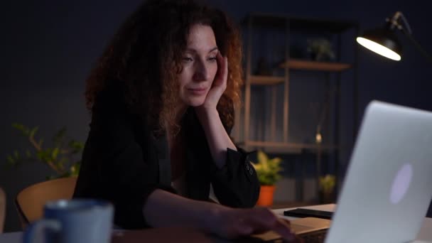 Διάρρηξη και προβλήματα στη δουλειά. Οικονομικές δυσκολίες. Στενή προσωπογραφία μιας απογοητευμένης γυναίκας που κρατάει το πρόσωπό της με τα χέρια της ενώ κάθεται στο γραφείο της αργά το βράδυ — Αρχείο Βίντεο