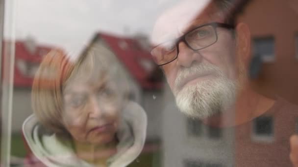 Starsze małżeństwo stojące razem przy oknie, opiekuńczy mąż przytulający żonę. Para w domu opieki podczas zamykania, samotności i depresji — Wideo stockowe