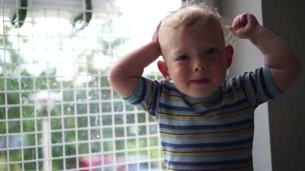 Dicht portret van een bezorgd jongetje op de kleuterschool. Het kind gebaart en probeert iets uit te leggen. De jongen is bezorgd. — Stockvideo
