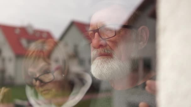 Pasangan lansia berdiri di samping jendela bersama-sama, suami yang peduli memeluk istri. Pasangan di panti jompo selama konsep penguncian, kesepian dan depresi — Stok Video