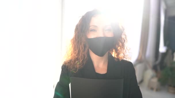 Potret dalam ruangan yang cerah dari seorang wanita bisnis berambut keriting yang cantik dalam topeng hitam dengan folder di tangannya — Stok Video
