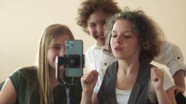 Üç genç okul çocuğu akıllı telefon ve dengeleyici kullanarak sosyal ağlar için komik bir video çekiyor.
