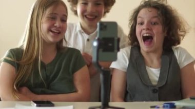 İki kız ve kıvırcık saçlı bir erkek sınıf arkadaşı bir aradayken okulda akıllı telefondan komik bir video izliyorlar. Sosyal medya eğilimleri kavramı