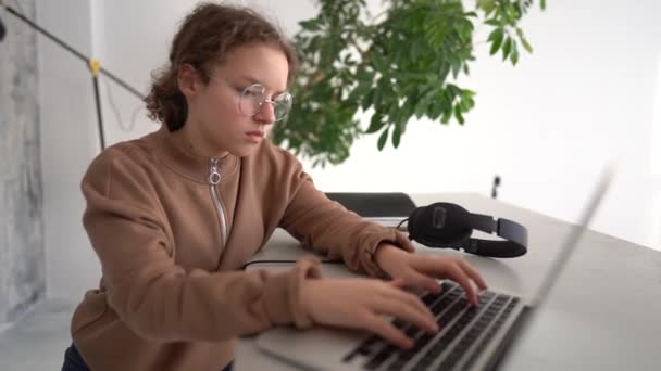 Крупним планом знімок серйозної дівчини-підлітка, задумливо дивлячись на екран ноутбука і друкуючи. Технології дистанційної освіти та домашнє завдання — стокове відео