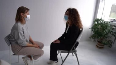 Meeting women in masks in the psychotherapists office during pandemic. Girls sit in pairs opposite each other and talk in the psychologists office. Womens circle concept, psychological help