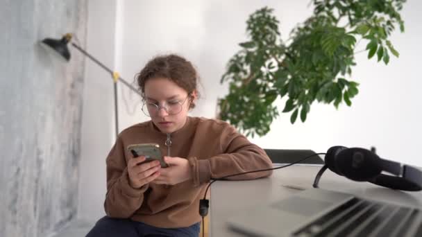 Close up portrait of a teenage girl wearing glasses with her smartphone. The girl communicates with friends at home. Distance learning during lockdown — ストック動画