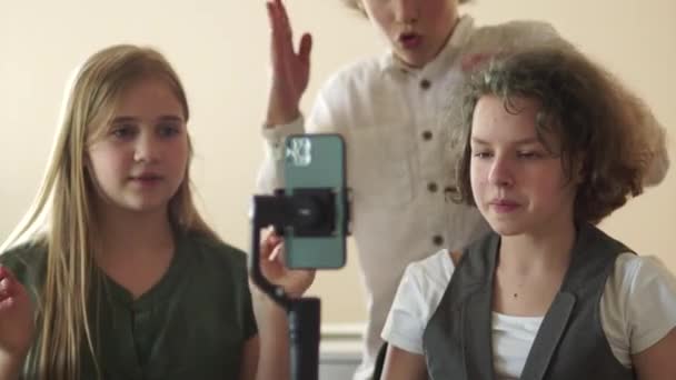 Portrait of funny schoolkids bloggers curly-haired teenage boy and girls with a steadicam. A schoolchildren is recording a stream from a school class. Video blogging and story concept — Vídeo de stock